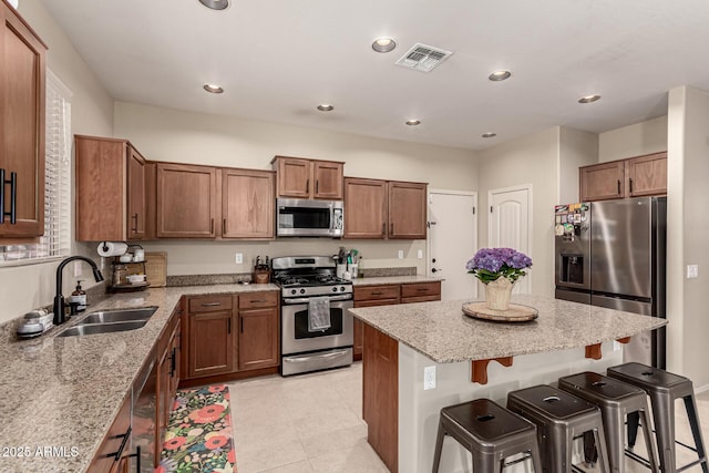 kitchen with a breakfast bar area, visible vents, appliances with stainless steel finishes, a center island, and a sink