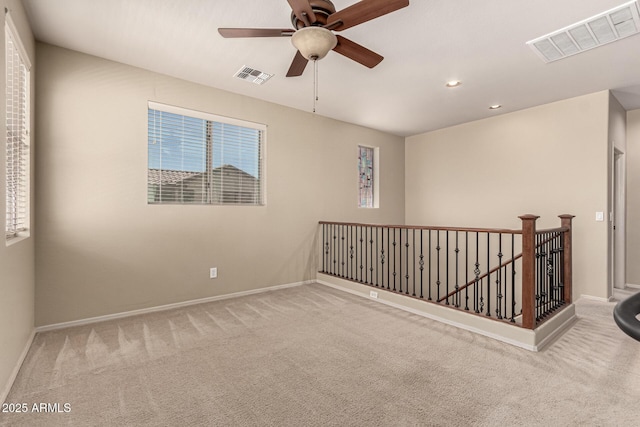 spare room with carpet floors, ceiling fan, visible vents, and baseboards