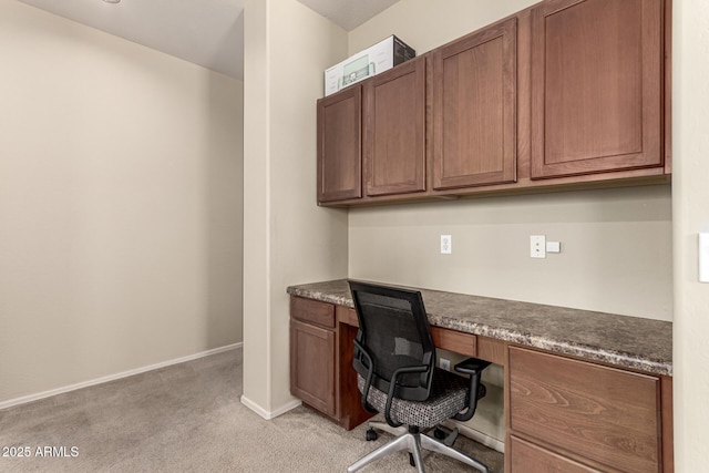office featuring baseboards, light carpet, and built in desk