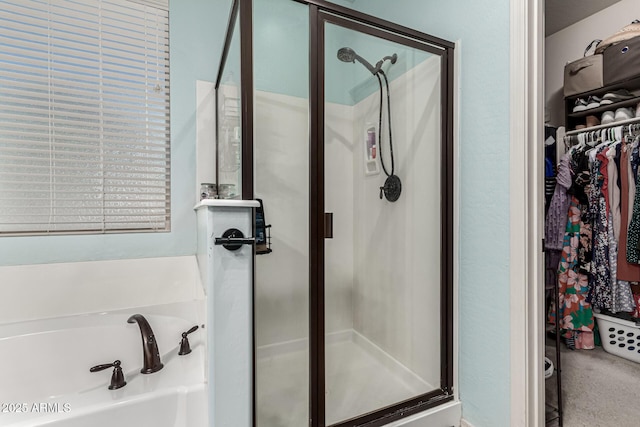full bathroom with a stall shower, a bath, and a spacious closet