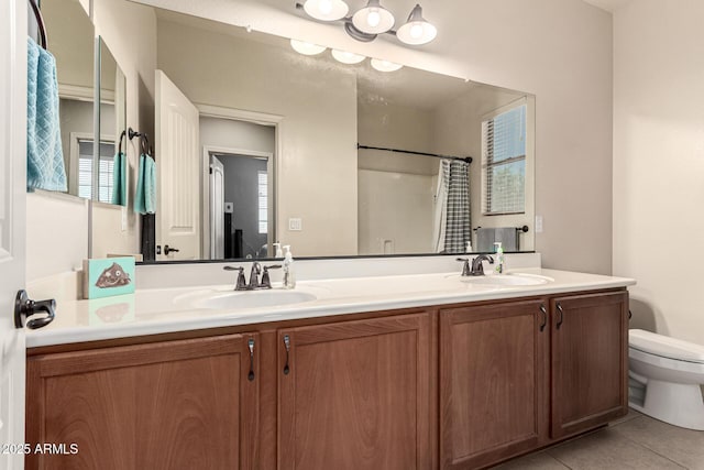 bathroom with a sink, tile patterned flooring, toilet, and double vanity