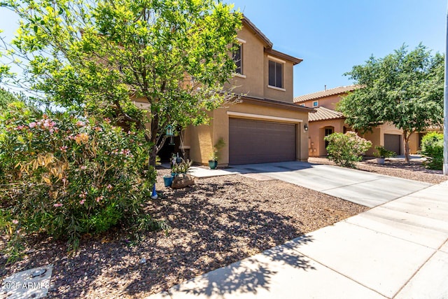 view of front of property with a tiled roof, a garage, driveway, and stucco siding