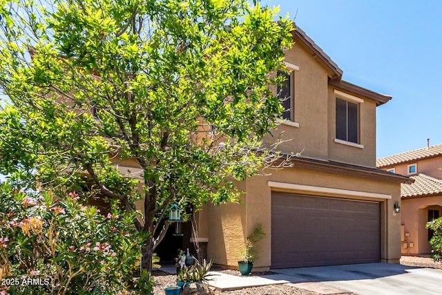 view of front of property featuring a garage, stucco siding, driveway, and a tile roof