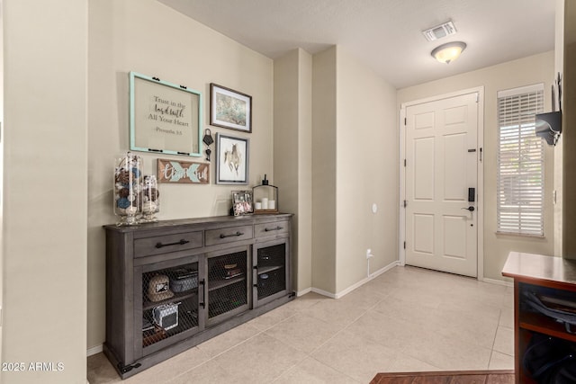 foyer entrance with baseboards, light tile patterned flooring, and visible vents