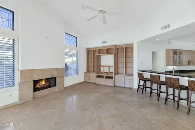 living room featuring a tile fireplace, high vaulted ceiling, a wealth of natural light, and ceiling fan