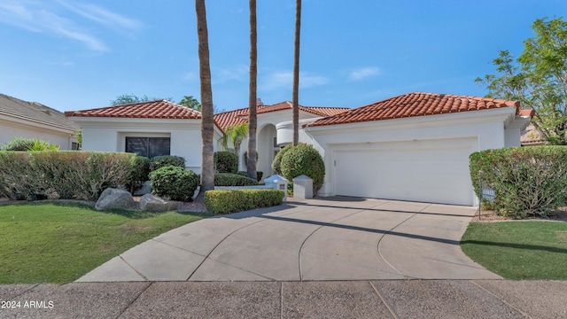 mediterranean / spanish-style house featuring a garage and a front lawn