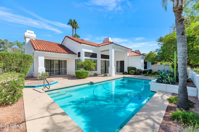 rear view of house featuring a patio and a fenced in pool