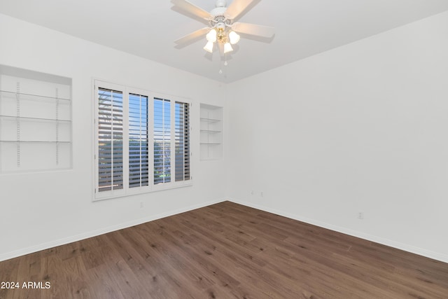 empty room featuring hardwood / wood-style floors, ceiling fan, and built in shelves