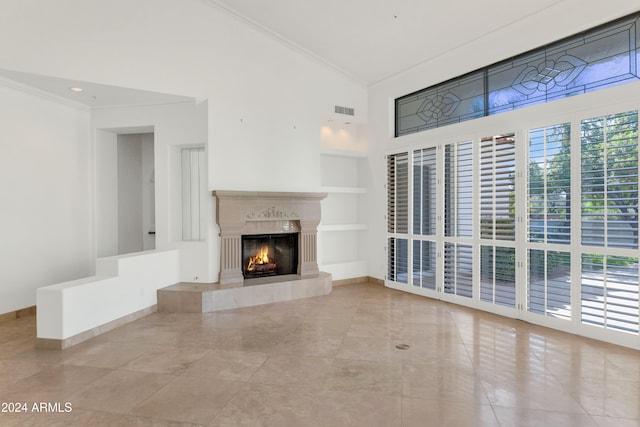 unfurnished living room with built in shelves, high vaulted ceiling, a tiled fireplace, light tile patterned flooring, and ornamental molding