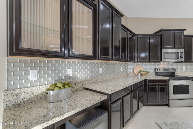 kitchen featuring backsplash, light stone counters, light tile patterned floors, and appliances with stainless steel finishes