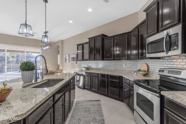 kitchen with sink, light tile patterned floors, appliances with stainless steel finishes, tasteful backsplash, and decorative light fixtures