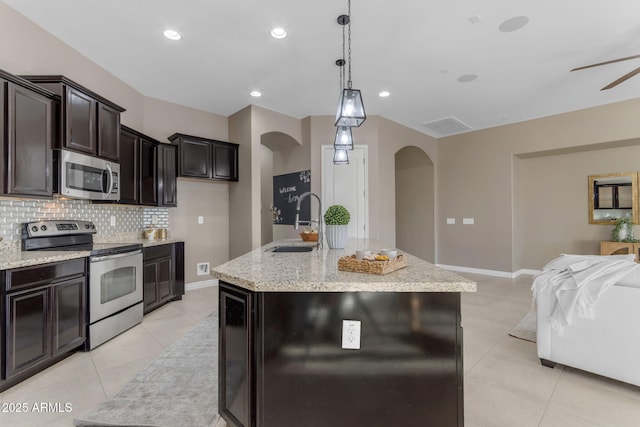 kitchen with pendant lighting, sink, stainless steel appliances, and an island with sink