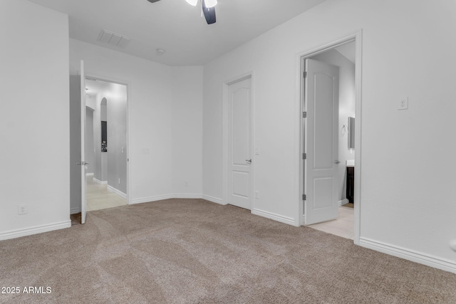 unfurnished bedroom with light colored carpet, ensuite bath, and ceiling fan