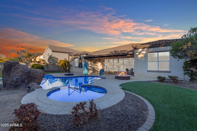 pool at dusk with a patio area, an outdoor fire pit, and a hot tub