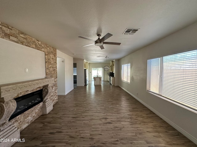 unfurnished living room featuring ceiling fan, hardwood / wood-style flooring, and a textured ceiling