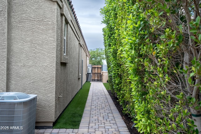 view of home's exterior with a gate, central AC unit, and stucco siding