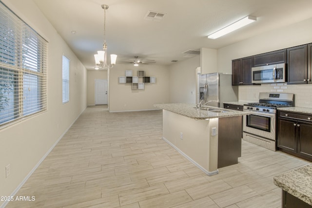 kitchen with stainless steel appliances, dark brown cabinets, decorative light fixtures, and tasteful backsplash