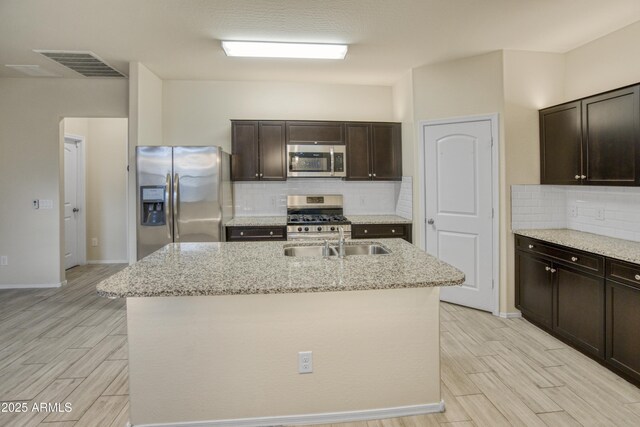 kitchen featuring light stone countertops, visible vents, stainless steel appliances, and wood finish floors