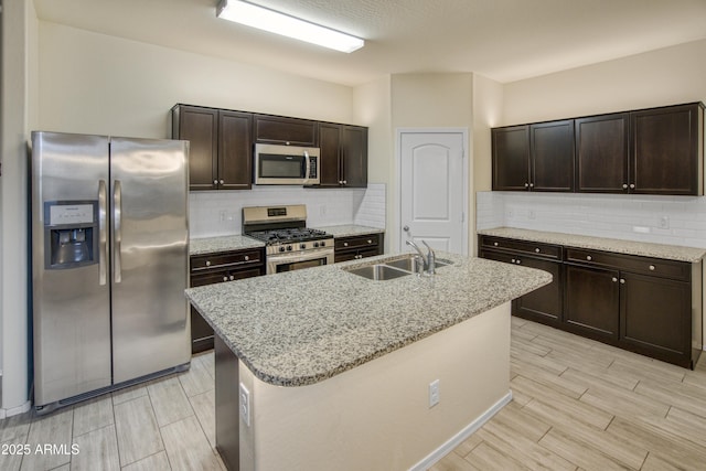 kitchen featuring stainless steel appliances, dark brown cabinets, a sink, and light stone counters