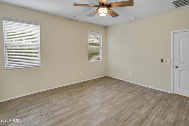 spare room with visible vents, ceiling fan, light wood-style flooring, and baseboards