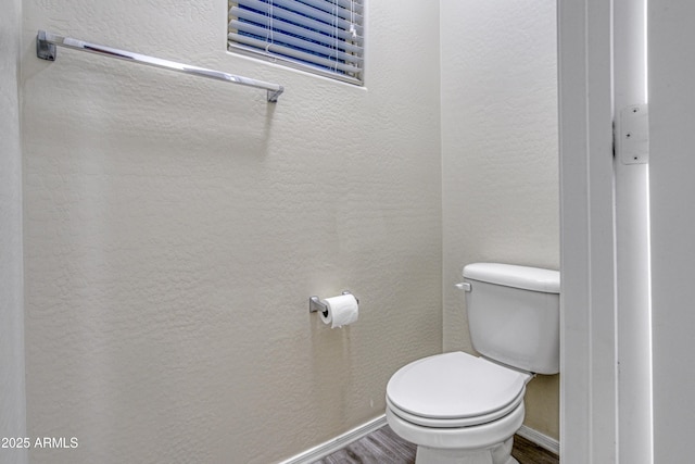 bathroom with baseboards, a textured wall, toilet, and wood finished floors