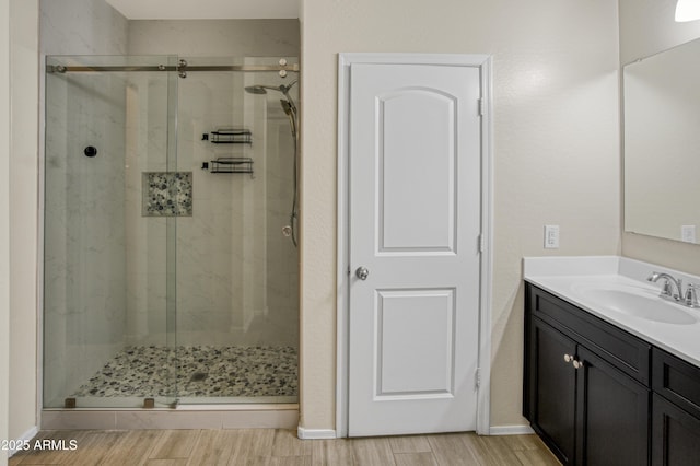 bathroom featuring a stall shower, wood finish floors, vanity, and baseboards