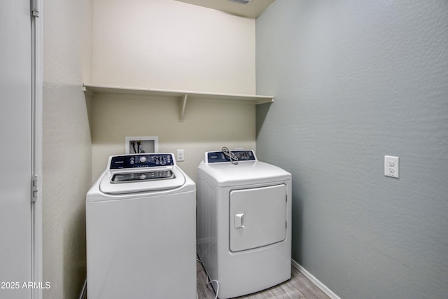 washroom featuring washer and clothes dryer, a textured wall, light wood-type flooring, laundry area, and baseboards