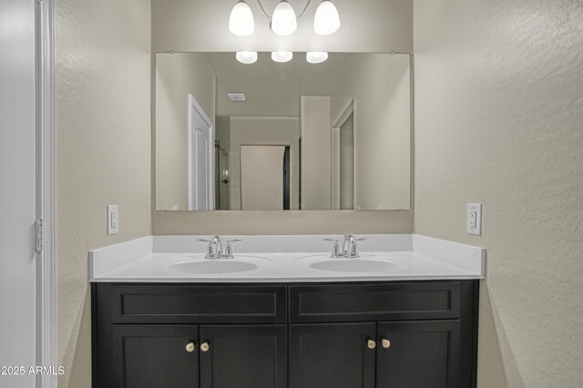 bathroom featuring a textured wall, double vanity, and a sink