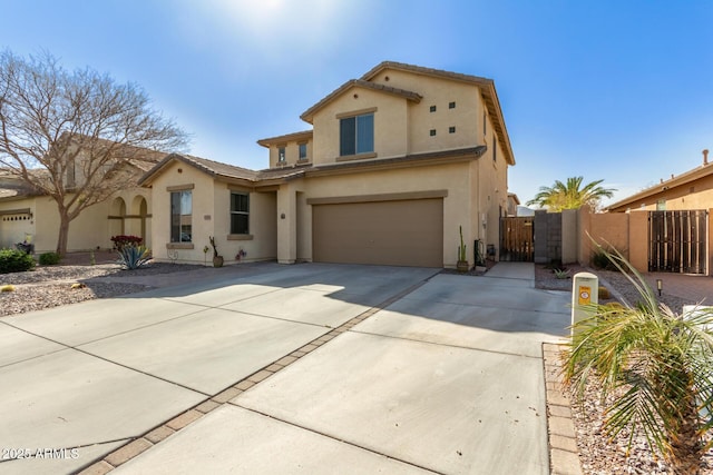 mediterranean / spanish-style home featuring driveway, a garage, a gate, fence, and stucco siding