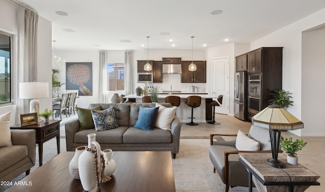 living room with a chandelier, sink, and light hardwood / wood-style flooring