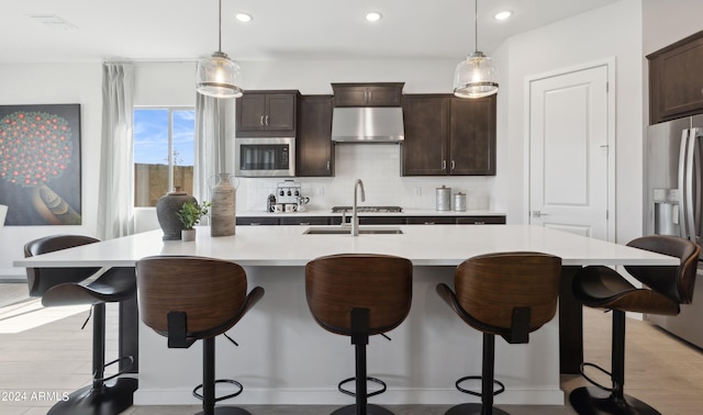 kitchen featuring range hood, an island with sink, and stainless steel appliances