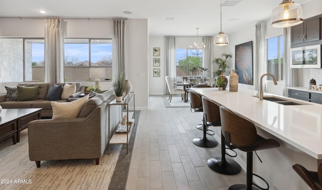 kitchen featuring sink, a breakfast bar area, an inviting chandelier, hanging light fixtures, and light hardwood / wood-style flooring