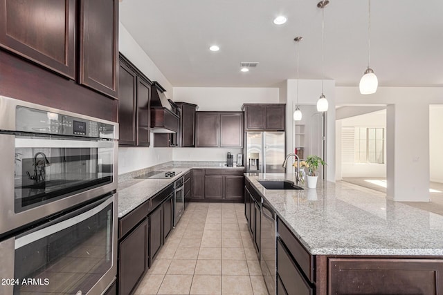 11122 E Tripoli Ave, Mesa, AZ 85212 - kitchen with appliances with stainless steel finishes, a large island with sink, dark brown cabinetry, hanging light fixtures, and light stone counters