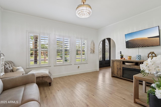 4735 E Harmony Cir, Mesa, AZ 85206 - living area featuring crown molding, arched walkways, a chandelier, light wood-style floors, and french doors