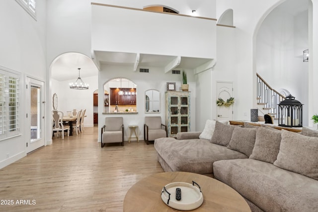 4735 E Harmony Cir, Mesa, AZ 85206 - living area with a towering ceiling, light wood-style floors, stairs, arched walkways, and a chandelier