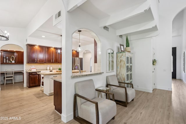 4735 E Harmony Cir, Mesa, AZ 85206 - kitchen with freestanding refrigerator, arched walkways, a breakfast bar, light wood-style floors, and backsplash
