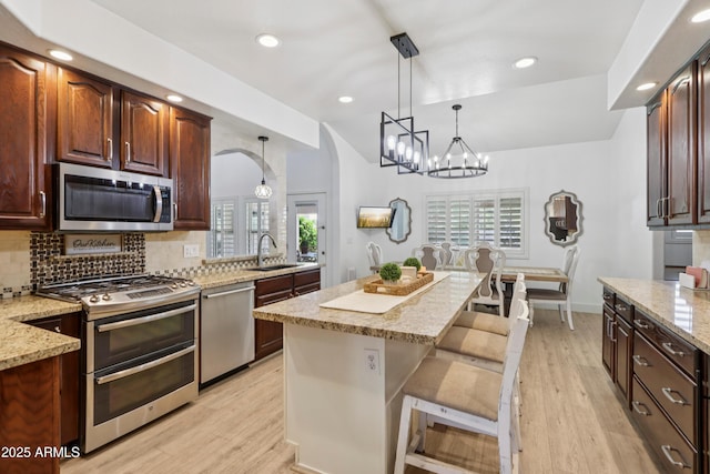 4735 E Harmony Cir, Mesa, AZ 85206 - kitchen with stainless steel appliances, a chandelier, arched walkways, tasteful backsplash, and light stone countertops