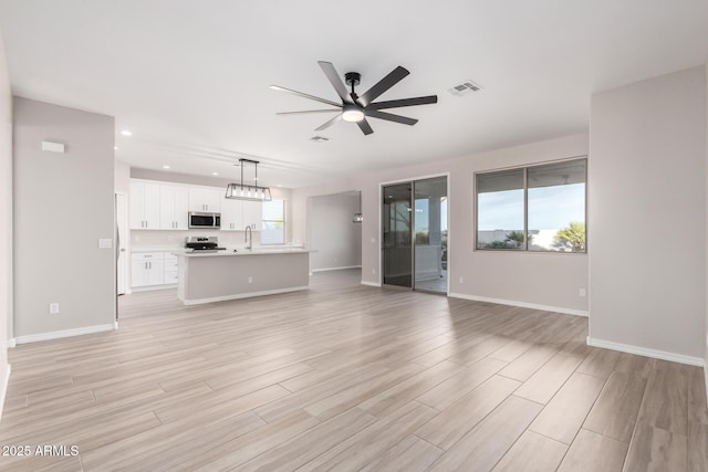 unfurnished living room featuring baseboards, visible vents, ceiling fan, and light wood finished floors