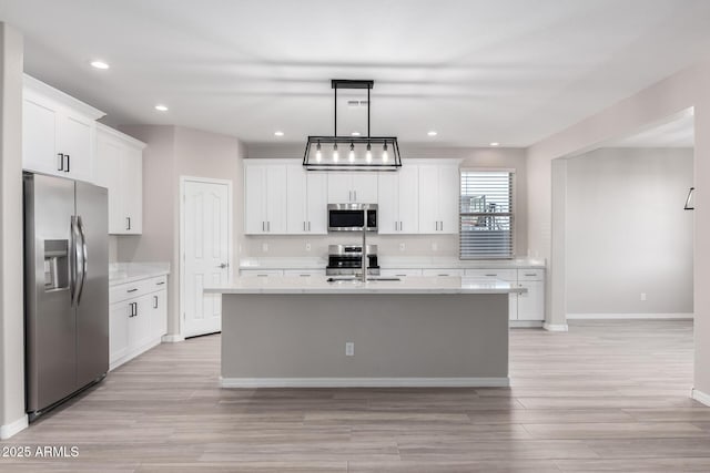 kitchen with a center island with sink, hanging light fixtures, stainless steel appliances, light countertops, and a sink