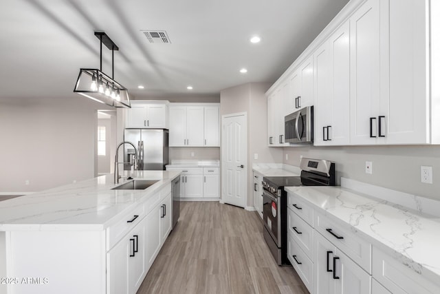 kitchen featuring white cabinets, stainless steel appliances, visible vents, and pendant lighting