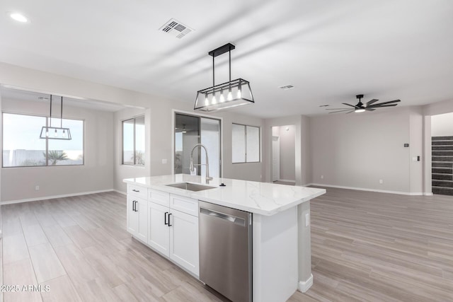 kitchen featuring open floor plan, decorative light fixtures, dishwasher, and a sink