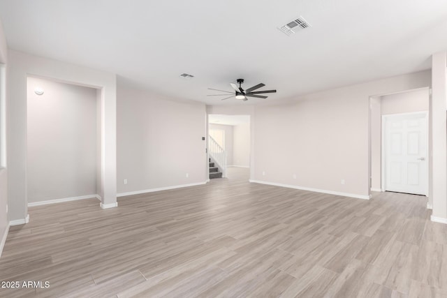 unfurnished living room featuring light wood finished floors, baseboards, visible vents, a ceiling fan, and stairs