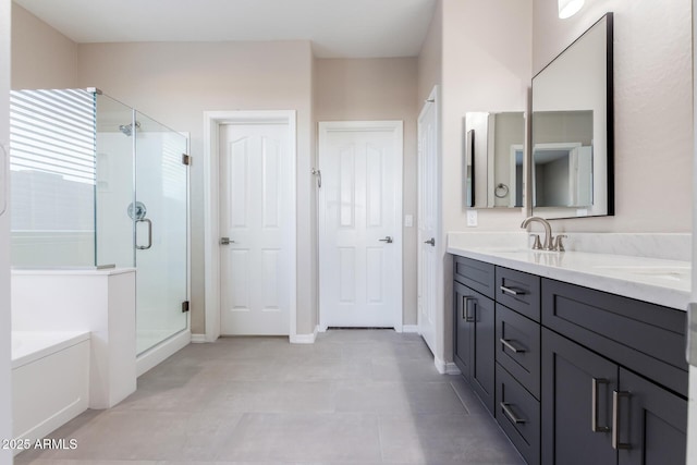 full bathroom with a garden tub, double vanity, a sink, a shower stall, and baseboards