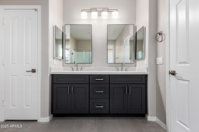 bathroom featuring double vanity, a sink, baseboards, and tile patterned floors