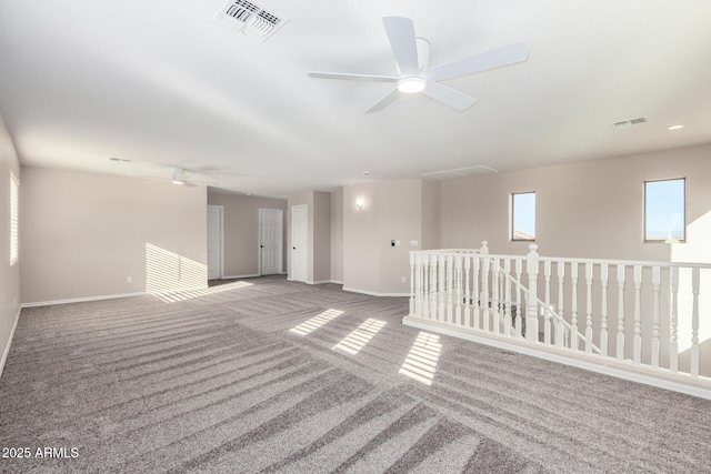 carpeted spare room featuring baseboards, visible vents, and a ceiling fan