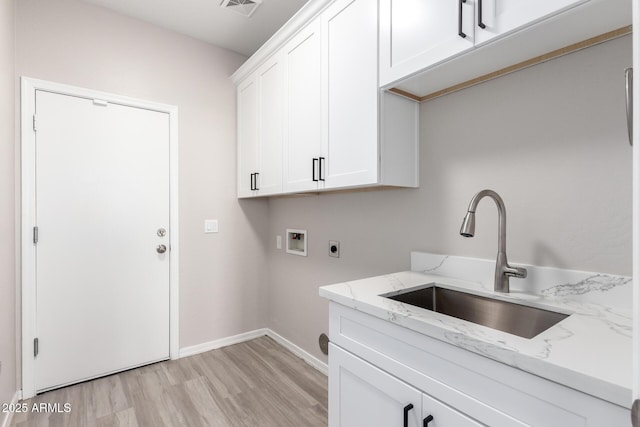 laundry room with hookup for a washing machine, cabinet space, light wood-style floors, a sink, and electric dryer hookup