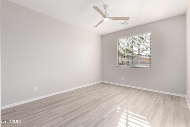 empty room featuring ceiling fan, baseboards, visible vents, and light wood-style floors