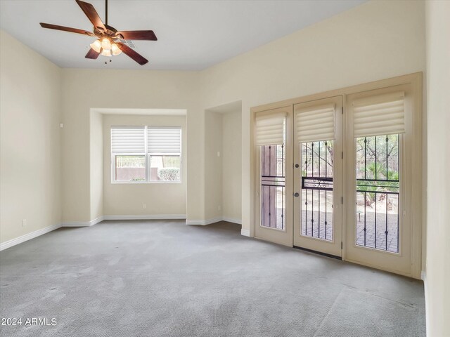 unfurnished room with light colored carpet, french doors, and ceiling fan