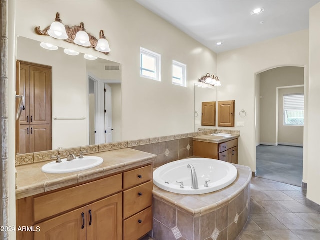 bathroom with tiled tub, vanity, and tile patterned floors