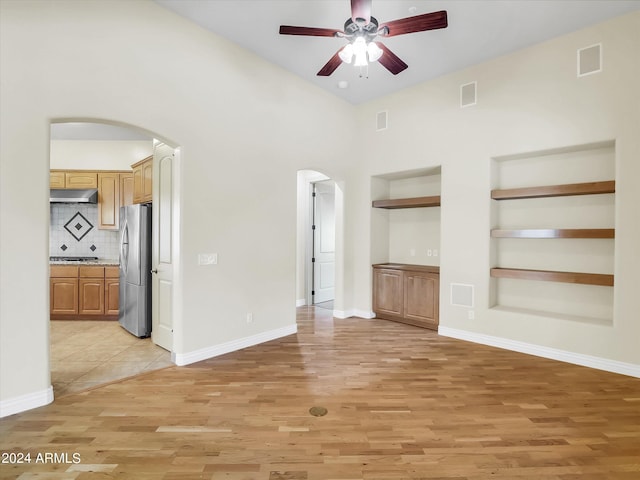 unfurnished living room featuring ceiling fan, light hardwood / wood-style floors, and built in shelves